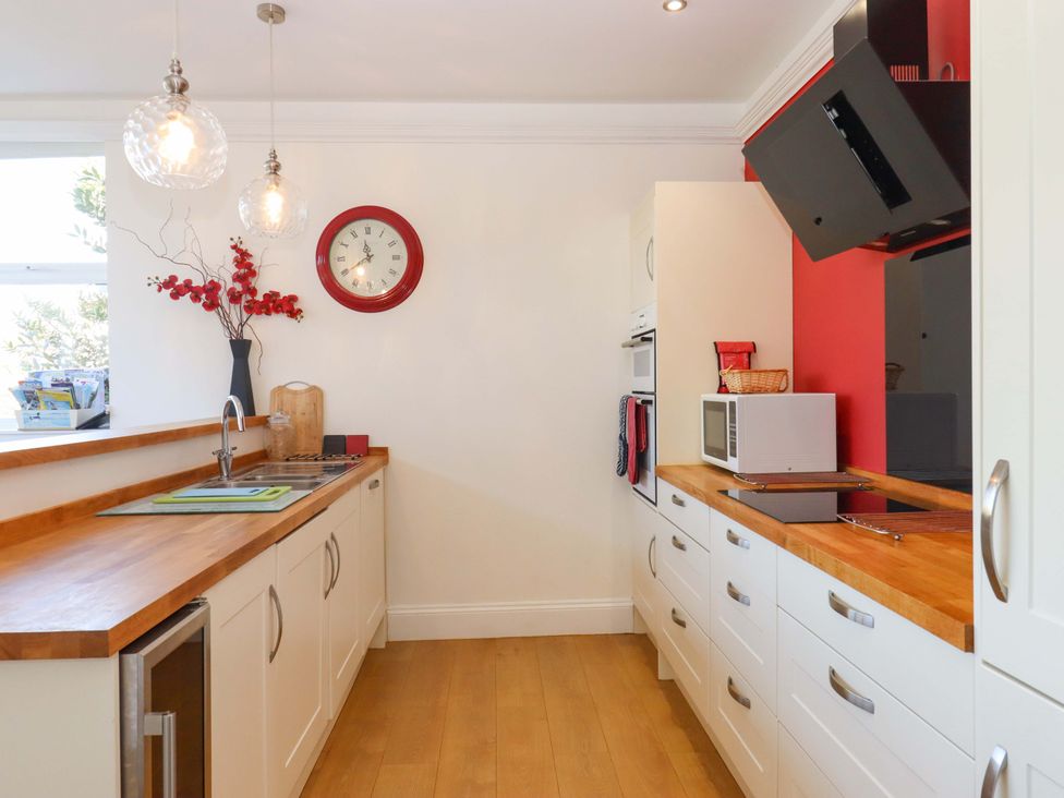 A kitchen with a sink, clock, and microwave at Avenue Park Villa in Torquay