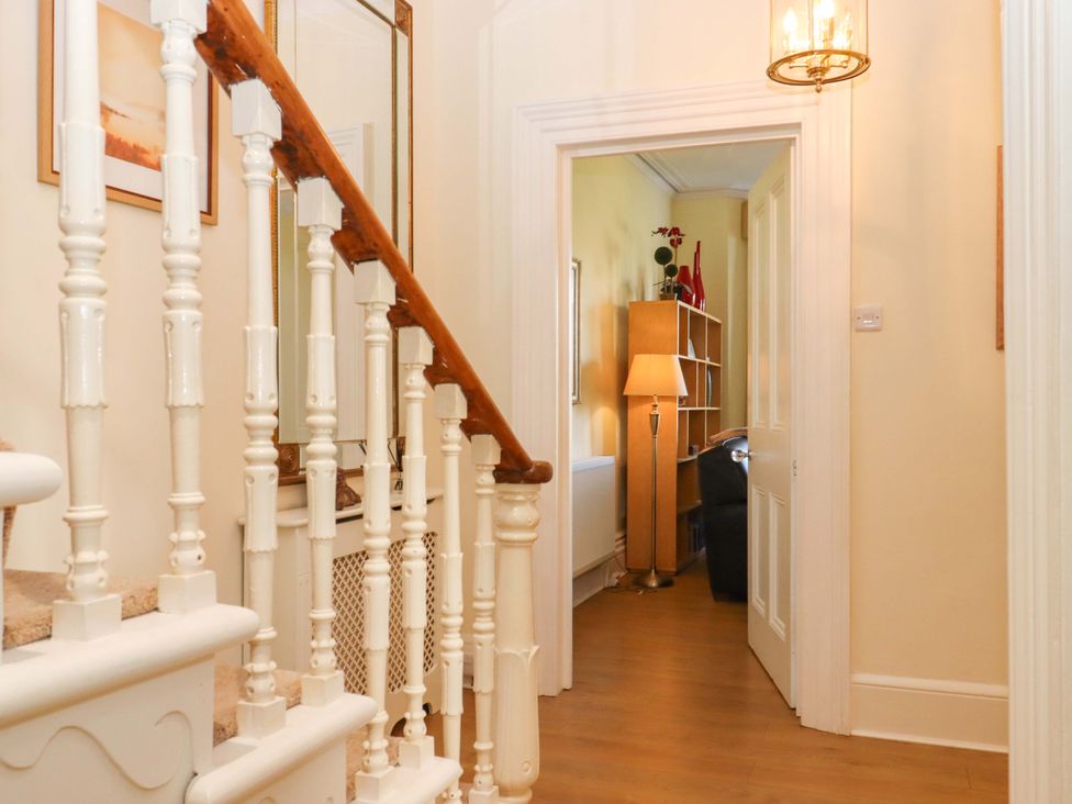 A hallway with a staircase and a bookcase at Avenue Park Villa Torquay