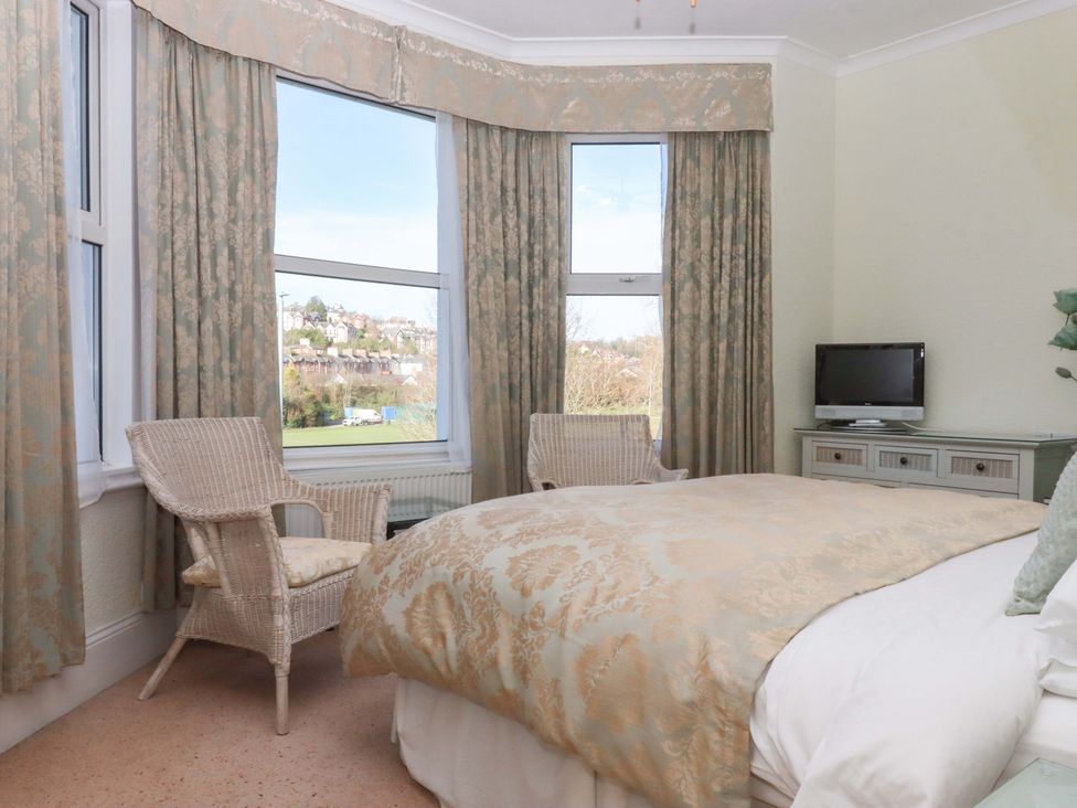 A bedroom with two armchairs and a television at Avenue Park Villa in Torquay