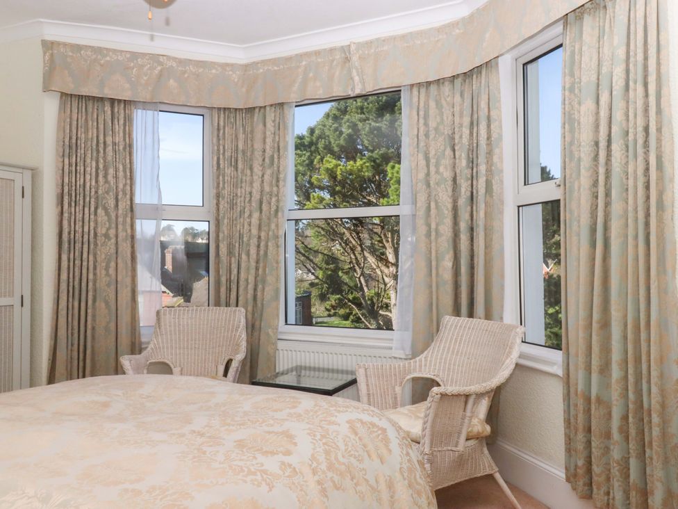 A bedroom with a bed and chairs at Avenue Park Villa in Torquay