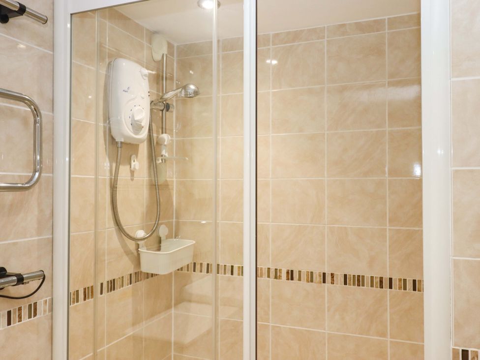 A shower with glass doors and a showerhead at Avenue Park Villa in Torquay