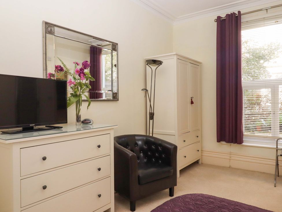 A bedroom with a TV, dresser, and chair at Avenue Park Villa in Torquay
