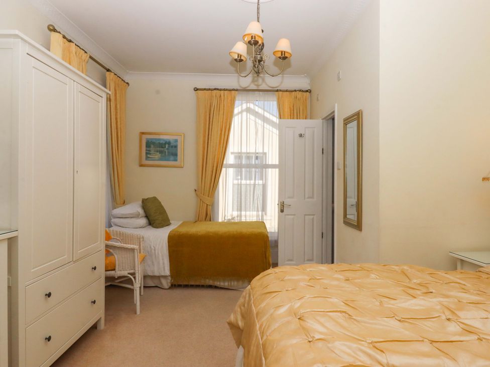 A bedroom with two beds and a wardrobe at Avenue Park Villa in Torquay