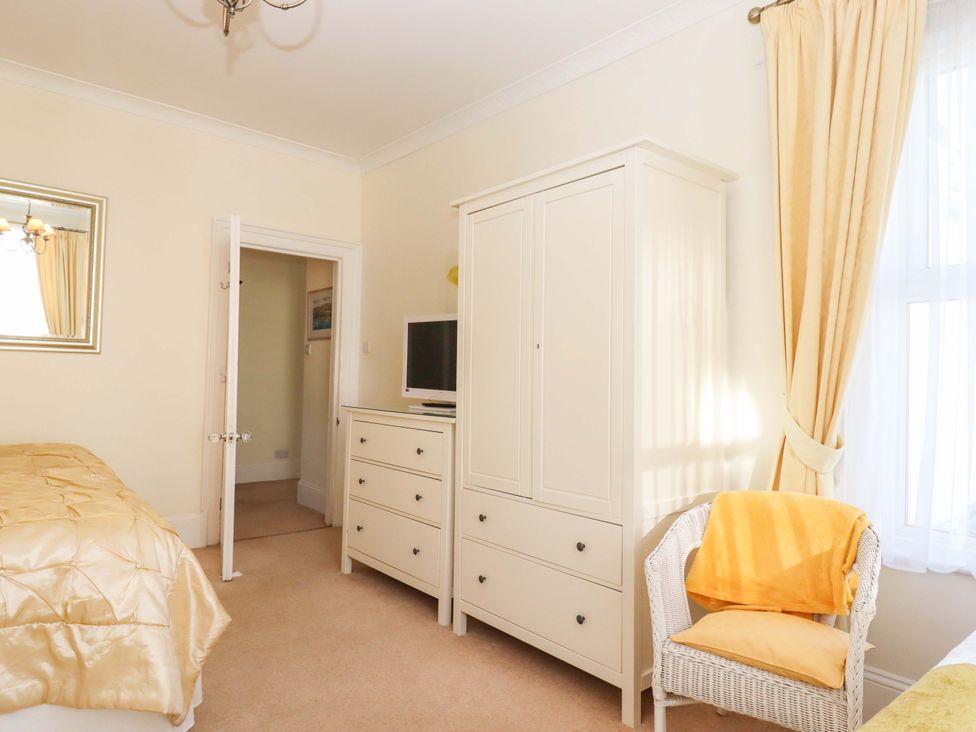 A bedroom with a bed, wardrobe, chest of drawers, and television at Avenue Park Villa in Torquay