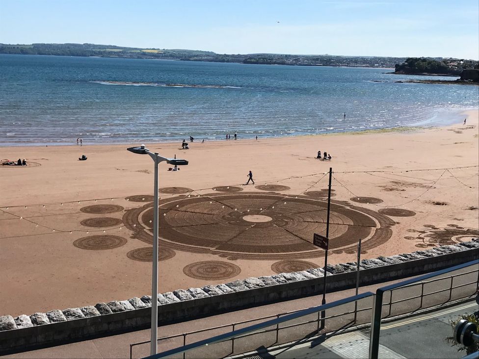 A beach with sand patterns and people at Avenue Park Villa in Torquay