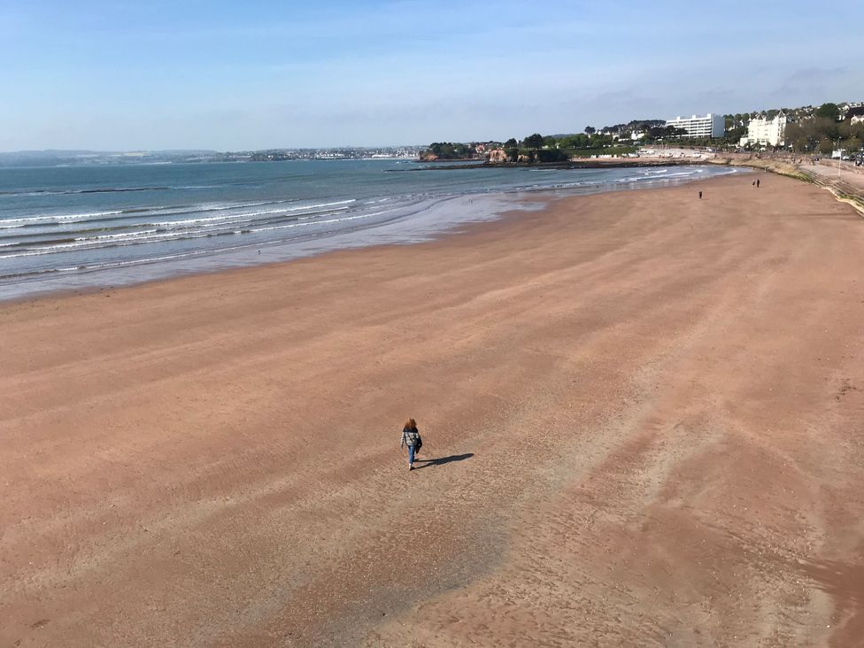 A beach with a person walking along the shore at Avenue Park Villa Torquay