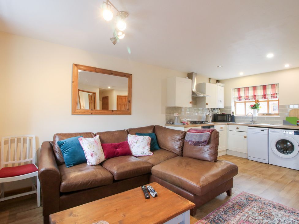 A living room with a sofa and kitchen area at Old Hall Barn 1 Church Stretton