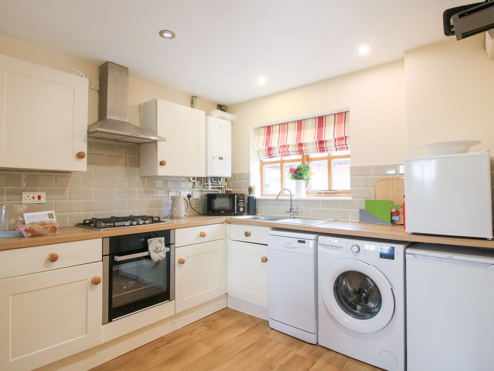 A kitchen with a cooker and washing machine at Old Hall Barn 1 Church Stretton