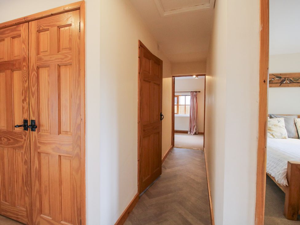 A hallway with wooden doors and a window at Old Hall Barn 1 Church Stretton