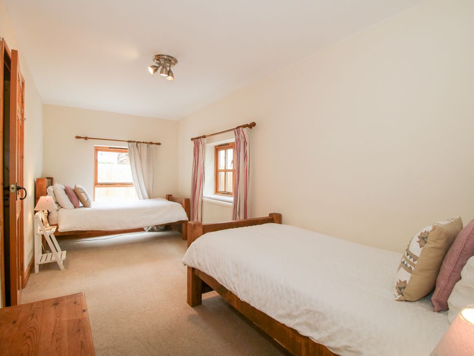 A bedroom with two beds and a window at Old Hall Barn 1 Church Stretton