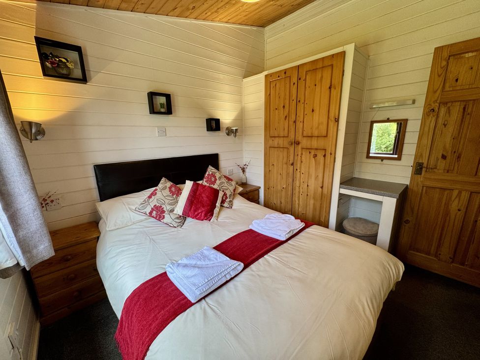 A bedroom with a bed and wardrobe at Willow Lodge in Constantine near Falmouth