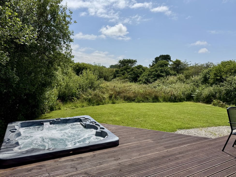 A hot tub on a deck with garden view at Willow Lodge in Constantine near Falmouth