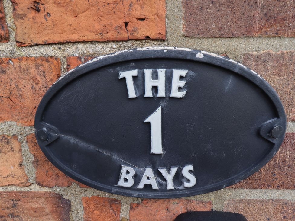 A plaque labeled 'The 1 Bays' on a brick wall at 1 The Bays Burgh Le Marsh