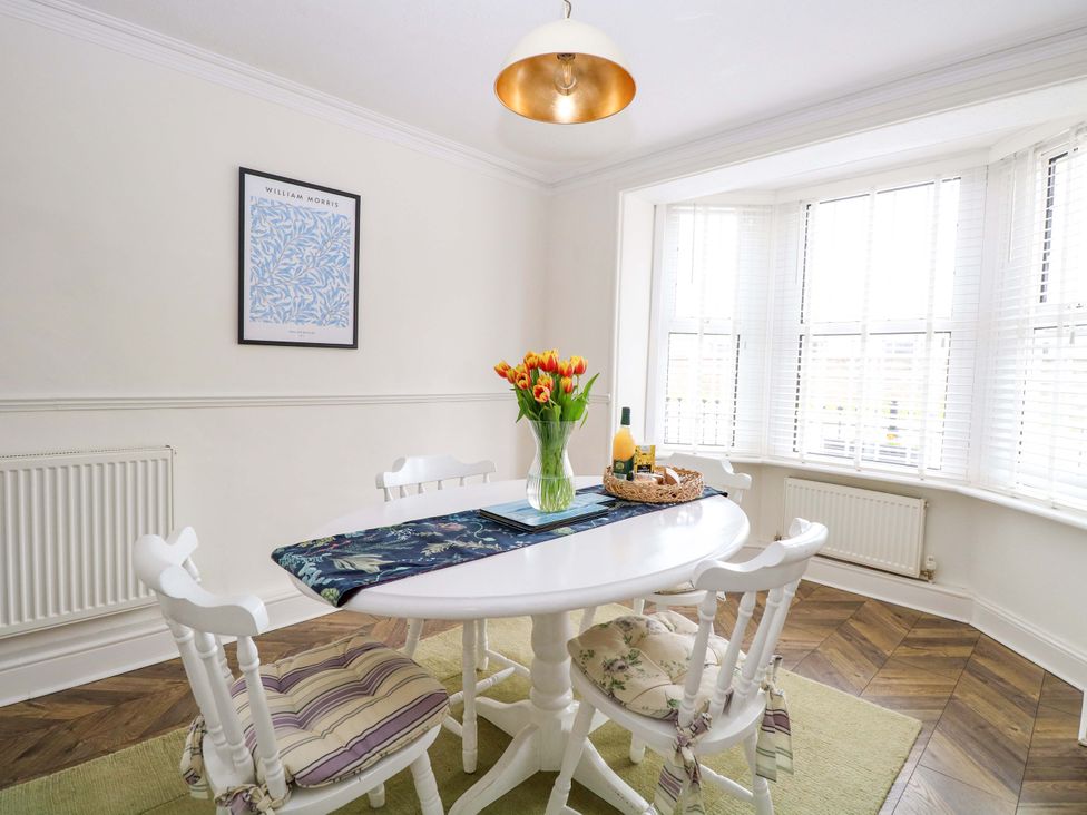 A dining room with a table, chairs, and a vase of tulips at Springfield in Hempton near Fakenham