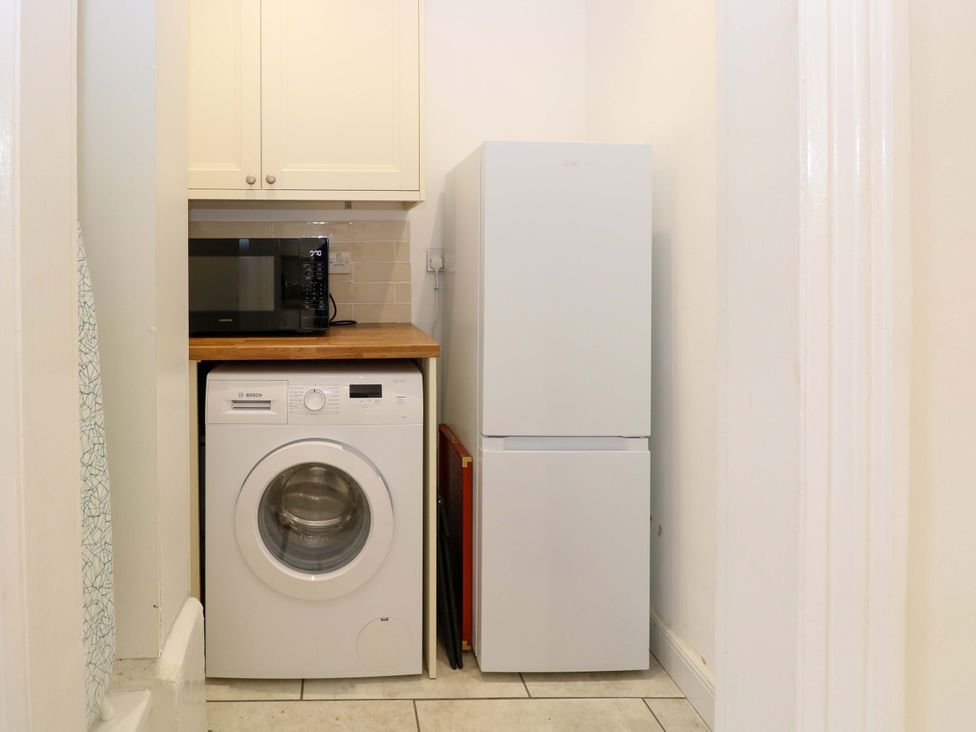 A utility room with washing machine refrigerator and microwave at Springfield in Hempton near Fakenham