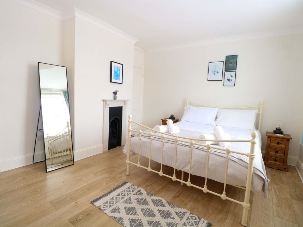 A bedroom with a bed, nightstand, and mirror at Springfield in Hempton near Fakenham