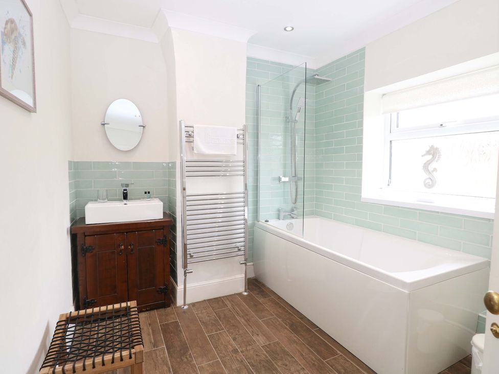 A bathroom with a bath tub, sink, and towel rack at Springfield in Hempton near Fakenham