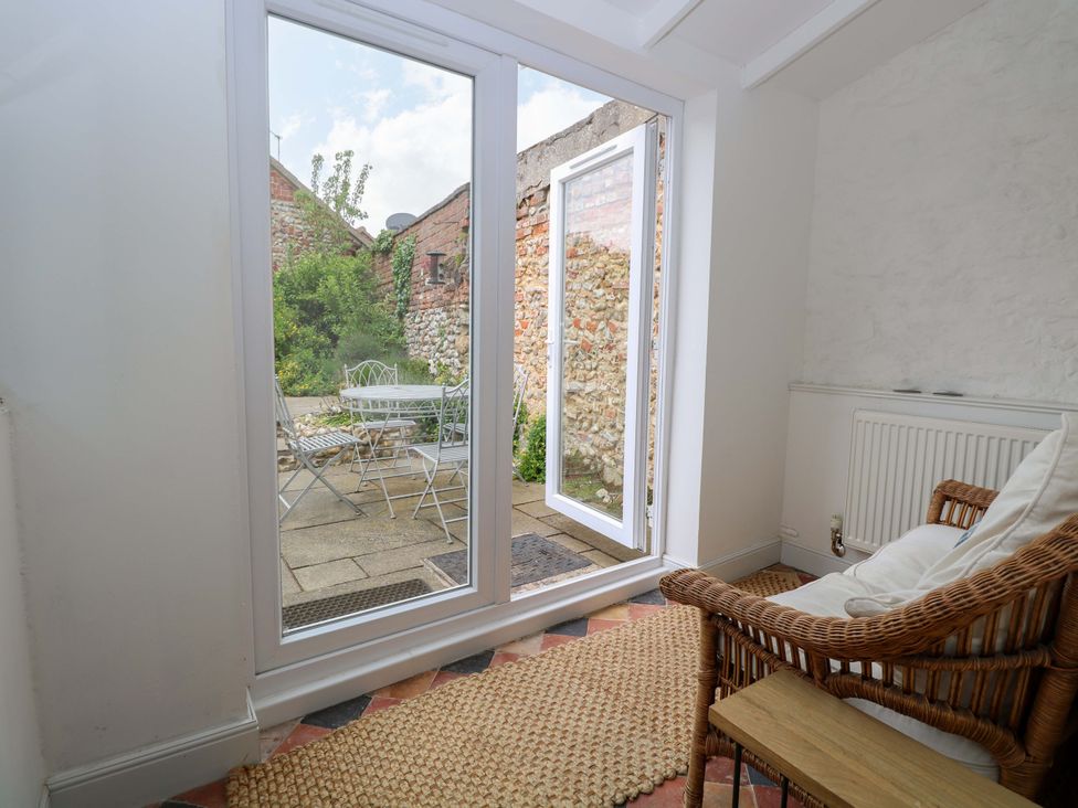 A sunroom with an armchair and a table at Springfield in Hempton near Fakenham