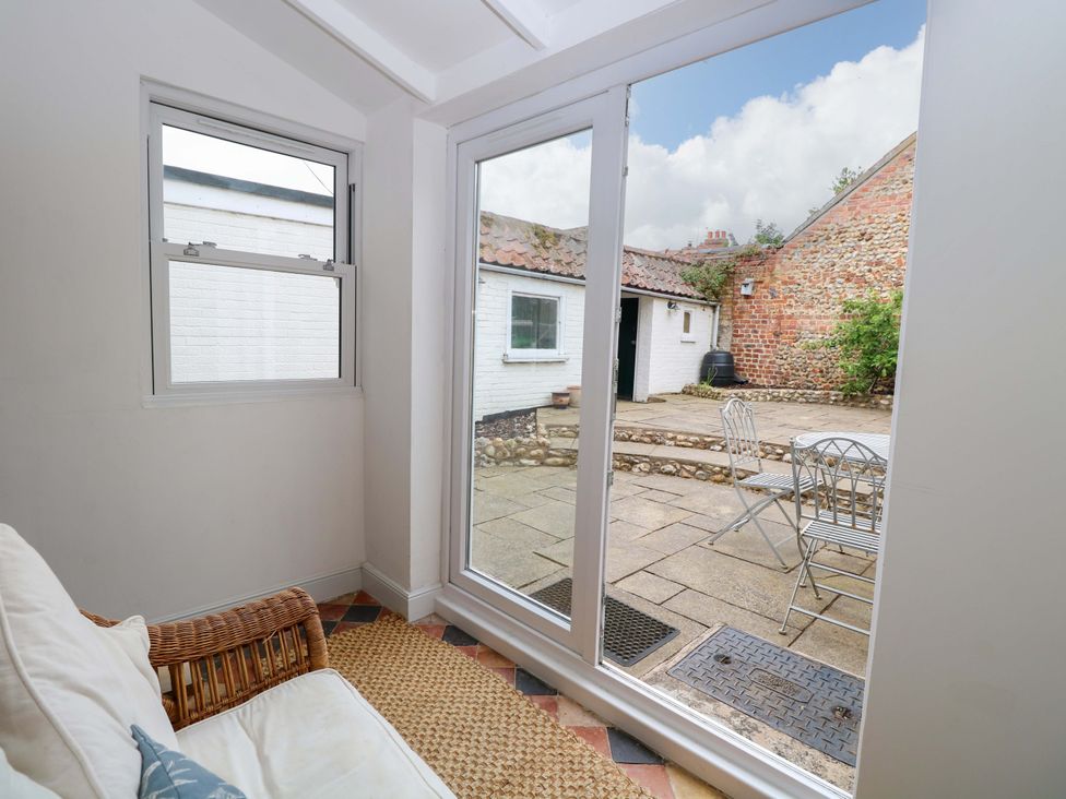 A conservatory with a sofa and view of patio at Springfield in Hempton near Fakenham