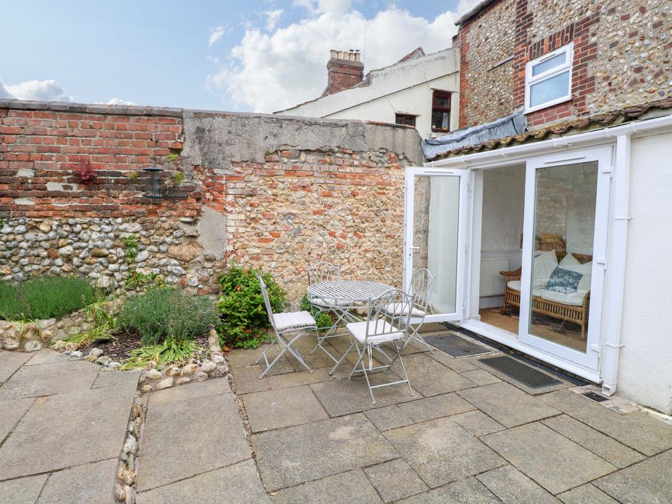A garden with a table and chairs near a brick wall at Springfield, Hempton near Fakenham