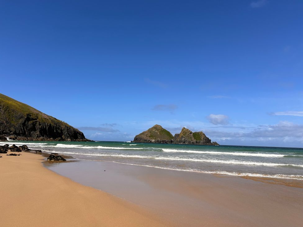A beach with sand and hills at Holywell Bay View in Holywell Bay
