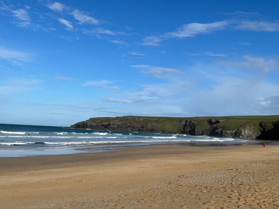 A beach with waves and cliffs at Holywell Bay View in Holywell Bay