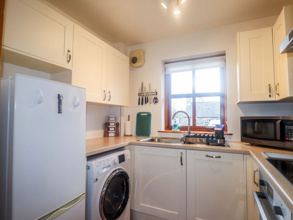A kitchen with a refrigerator, washing machine, and window at Church House in Poolewe