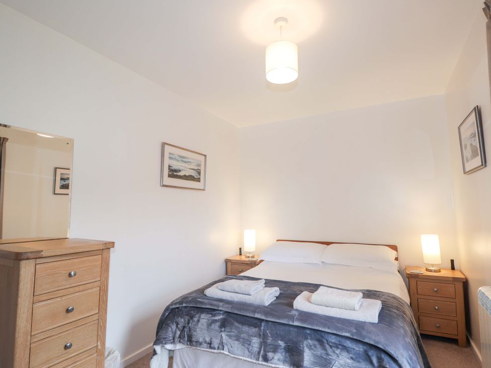 A bedroom featuring a bed with bedding and lamps at Church House in Poolewe
