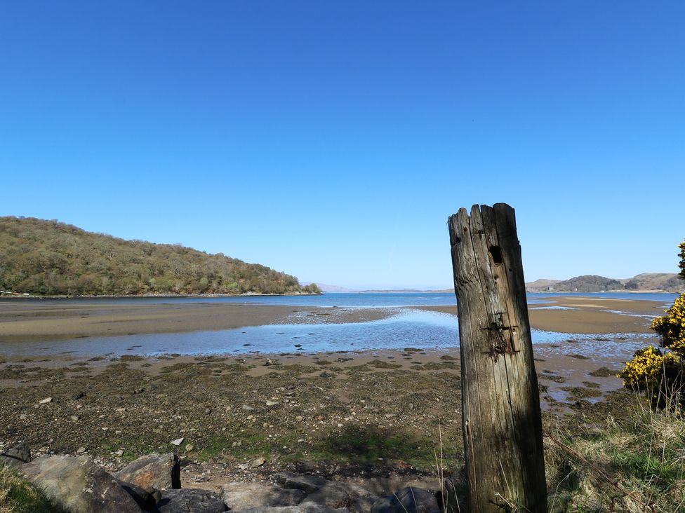 A landscape showing a wooden post by the water at Seaview-Barsloisnach Cottage in Kilmartin