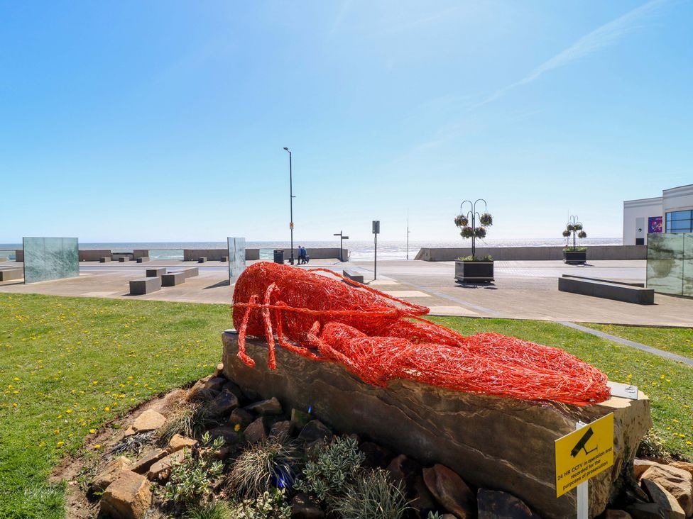A lobster sculpture on a stone base in a coastal area at Apt 5 @ Hunter's Quay in Bridlington