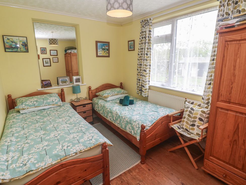 A bedroom with two beds and a wardrobe at Woolly Welcome Goldsithney