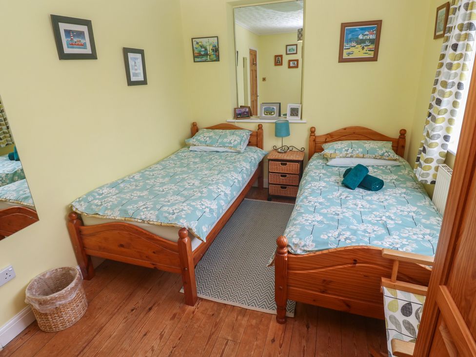 A bedroom with two single beds and a nightstand at Woolly Welcome in Goldsithney