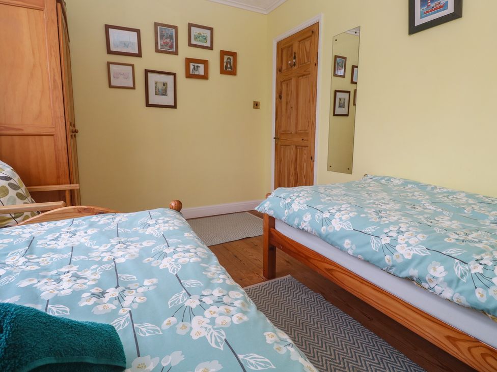 A bedroom with two beds and a wardrobe at Woolly Welcome in Goldsithney