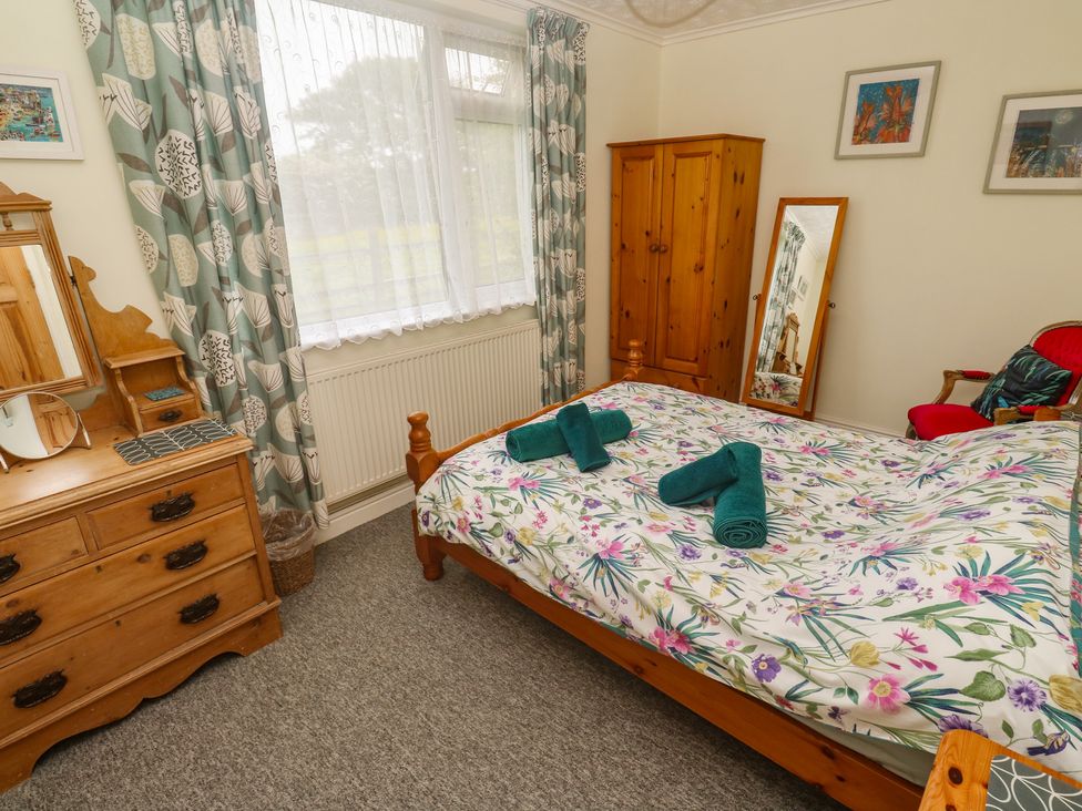 A bedroom with a bed and dresser at Woolly Welcome Goldsithney