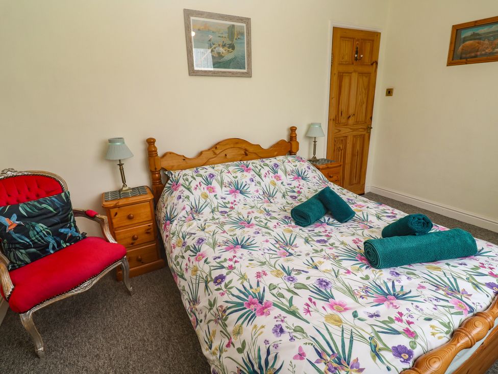 A bedroom with a bed and nightstand at Woolly Welcome in Goldsithney