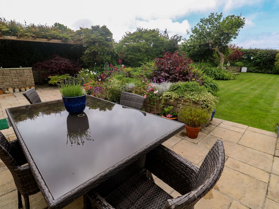 A garden with a table and chairs at Woolly Welcome in Goldsithney