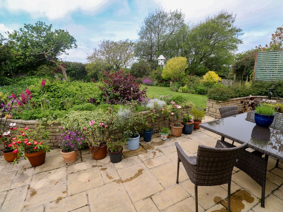 A garden with flower pots and seating area at Woolly Welcome in Goldsithney