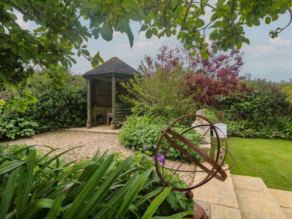 A gazebo with plants and an orbital structure in a garden at Woolly Welcome in Goldsithney