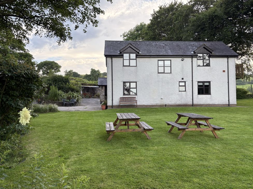 A house with picnic tables and a lawn at Garth Cottage Groes near Denbigh