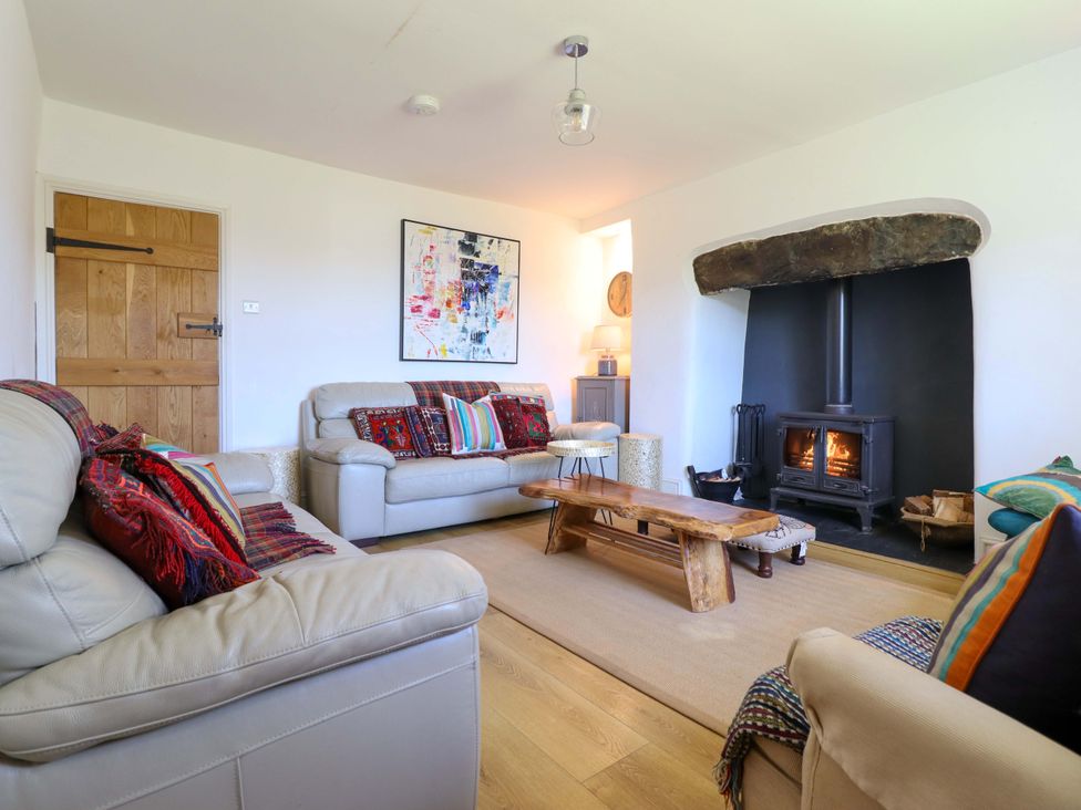 A living room with a fireplace and wooden table at Cefn Nannau near Ty-nant Cerrigydrudion