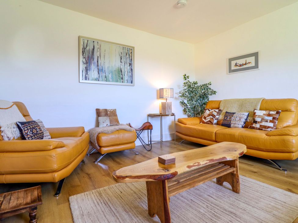 A living room with orange sofas and a wooden coffee table at Cefn Nannau near Ty-nant Cerrigydrudion