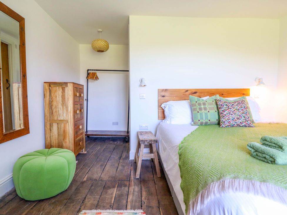 A bedroom with a bed, dresser, and stool at Cefn Nannau near Ty-nant Cerrigydrudion
