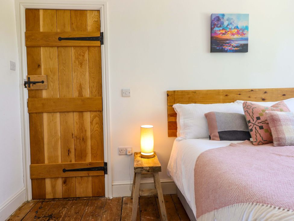 A bedroom with a bed, lamp, and wooden door at Cefn Nannau near Ty-nant Cerrigydrudion