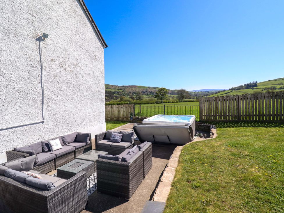An outdoor area with a hot tub and seating at Cefn Nannau Ty-nant near Cerrigydrudion