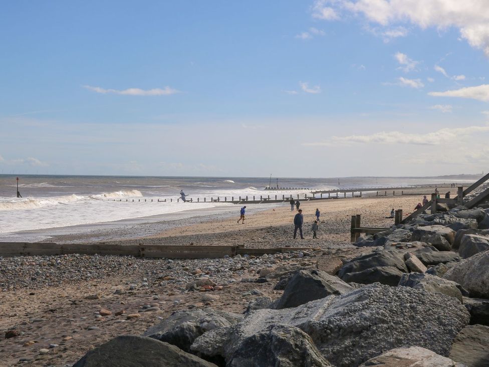A beach scene with waves and people walking at 8 Wilton Road Hornsea