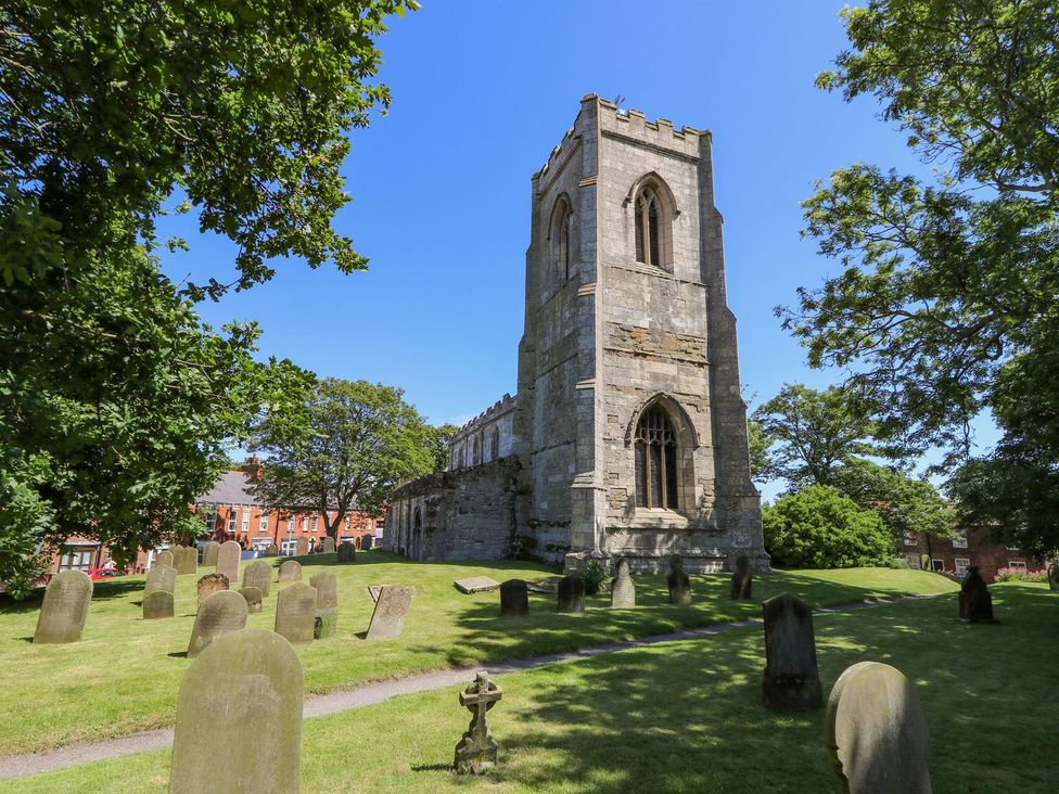 A church tower with gravestones in a cemetery at 8 Wilton Road Hornsea