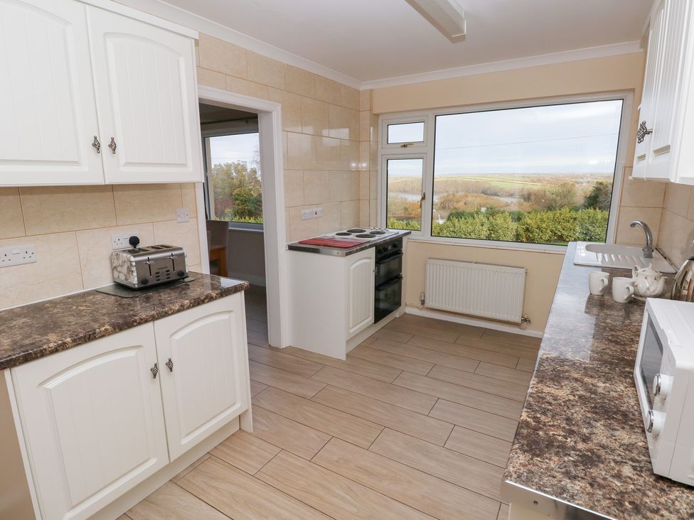 A kitchen with appliances and a large window at Cherry Trees in Haverfordwest