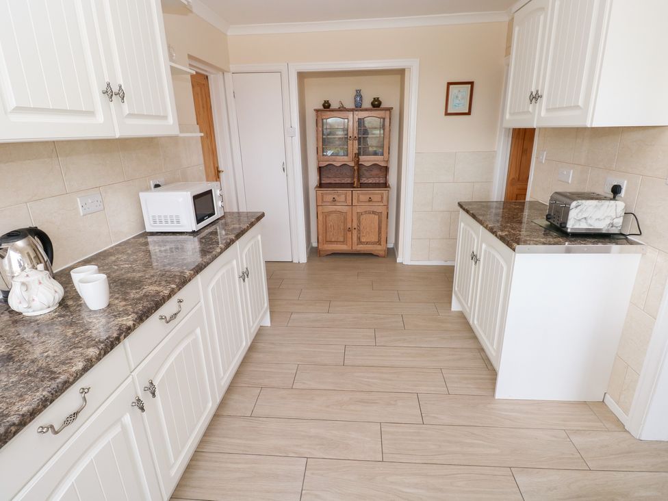 A kitchen with cabinets and appliances at Cherry Trees in Haverfordwest