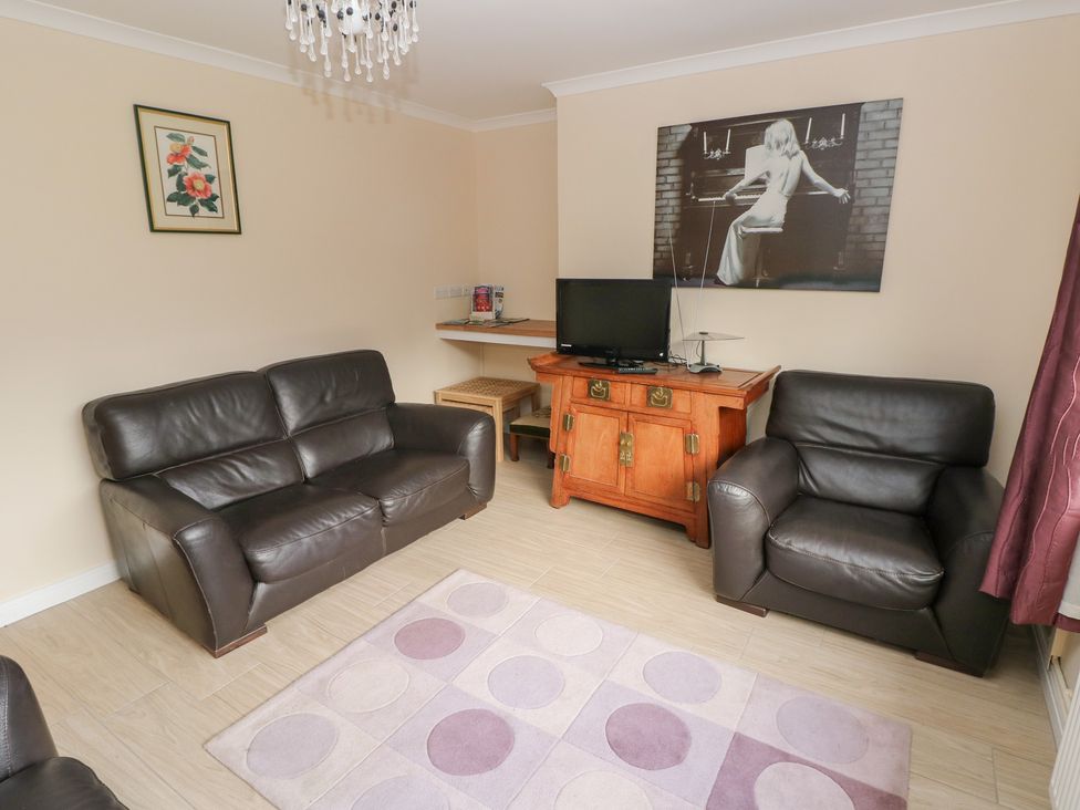 A living room with a television and seating at Cherry Trees in Haverfordwest