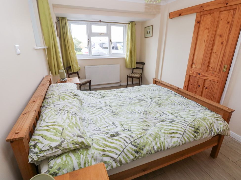 A bedroom with a bed and chair at Cherry Trees in Haverfordwest